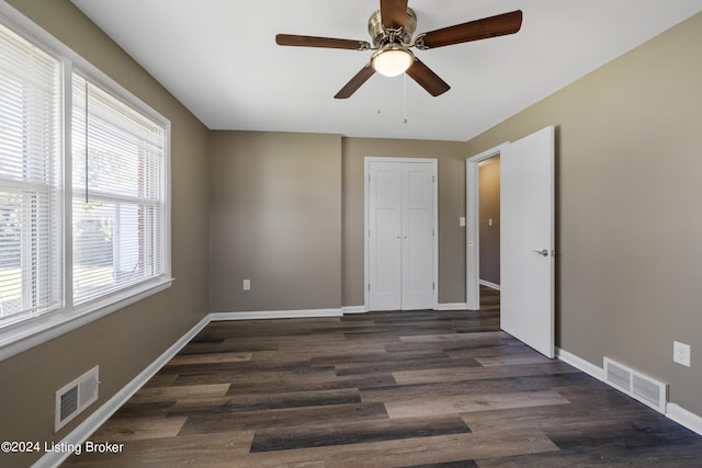 unfurnished bedroom featuring visible vents, baseboards, and dark wood-style floors