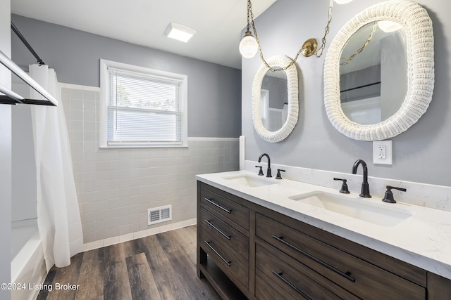 bathroom featuring visible vents, tile walls, wood finished floors, and a sink