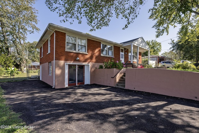 back of house with fence, brick siding, stairs, and a gate