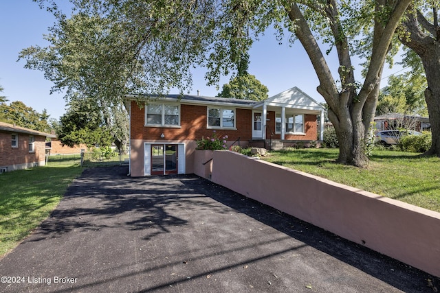 ranch-style house featuring brick siding, driveway, a front lawn, and fence