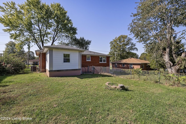 rear view of property featuring a lawn, a fenced backyard, and brick siding