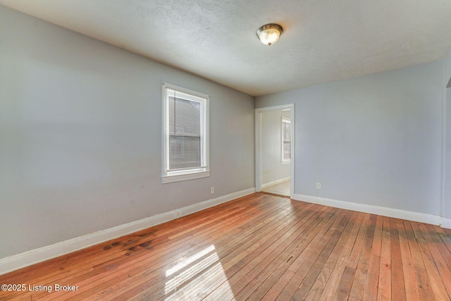 empty room featuring baseboards, a textured ceiling, and hardwood / wood-style floors