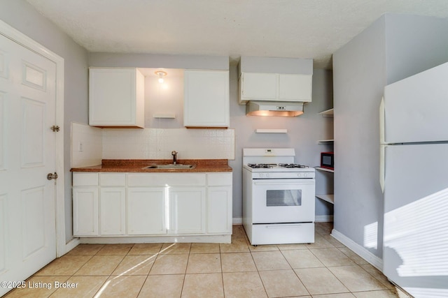 kitchen with decorative backsplash, light tile patterned flooring, white appliances, white cabinetry, and a sink