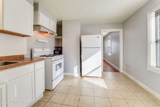 kitchen featuring white cabinetry, white appliances, light tile patterned flooring, and a healthy amount of sunlight