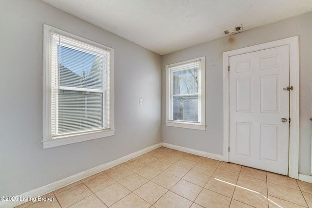 spare room with light tile patterned flooring, visible vents, and baseboards