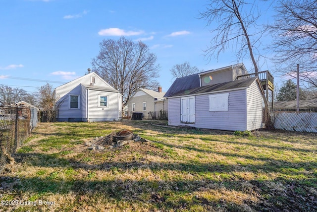 rear view of property with an outbuilding, a yard, a fire pit, and a fenced backyard