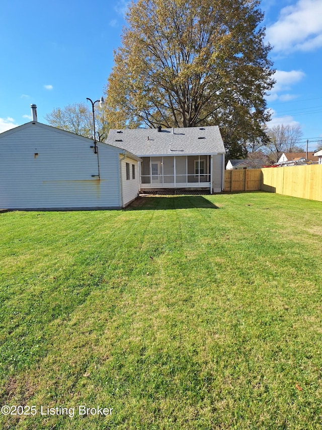 back of property featuring a yard, fence, and a sunroom