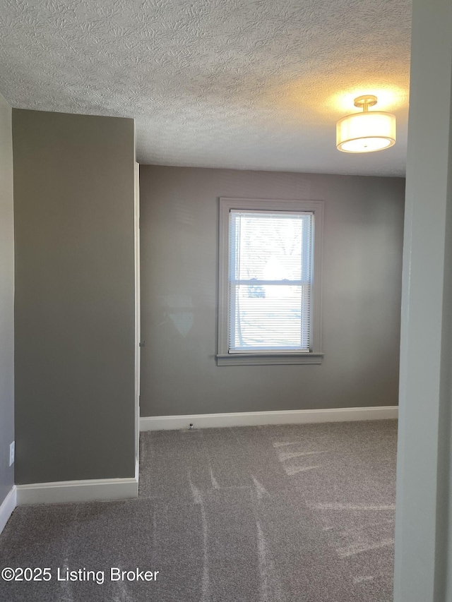 carpeted empty room with a textured ceiling and baseboards