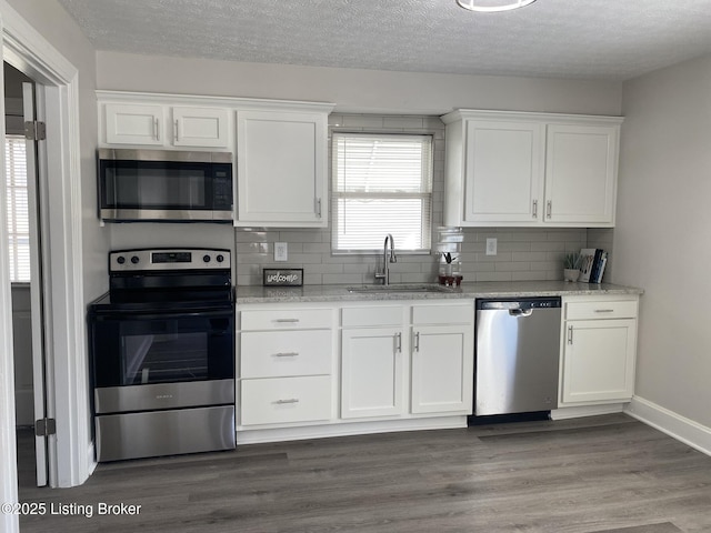 kitchen with a sink, stainless steel appliances, white cabinets, and dark wood-style flooring