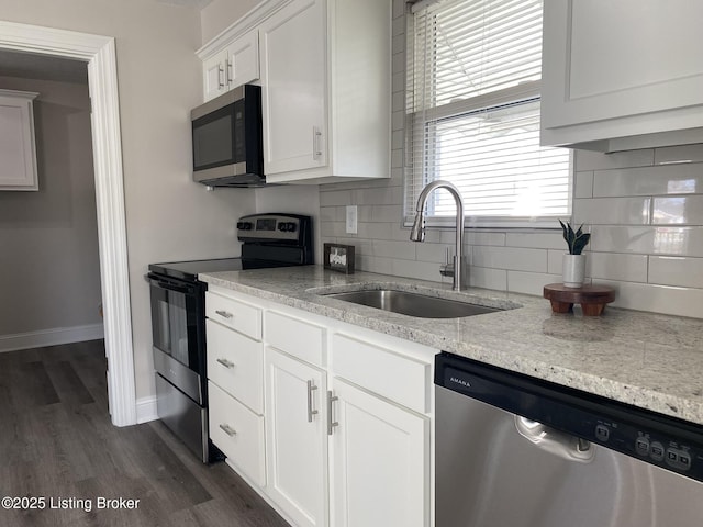 kitchen featuring dark wood-style floors, a sink, decorative backsplash, stainless steel appliances, and white cabinets