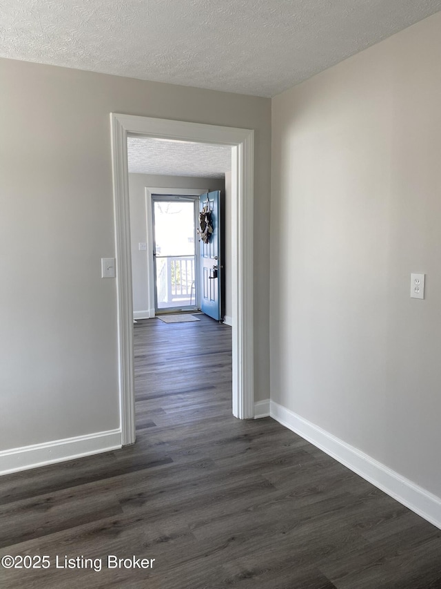 hallway with baseboards, a textured ceiling, and dark wood-style flooring