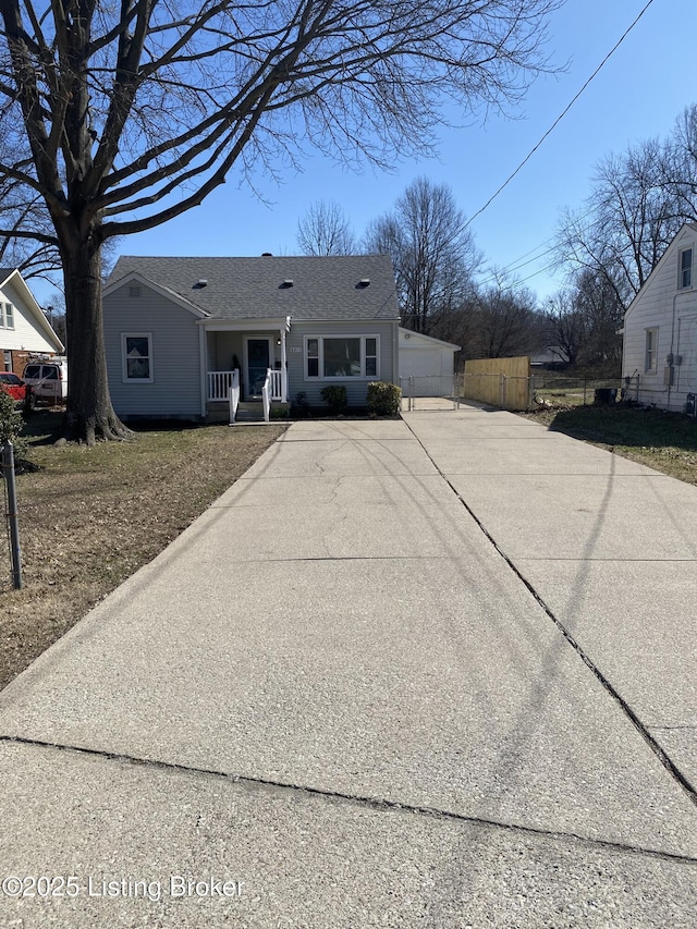 view of front of property featuring a porch, fence, driveway, and roof with shingles