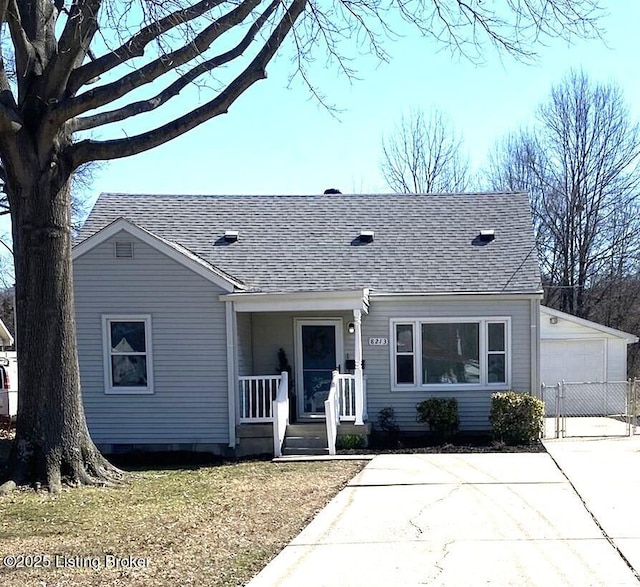 view of front facade with covered porch, roof with shingles, and a gate