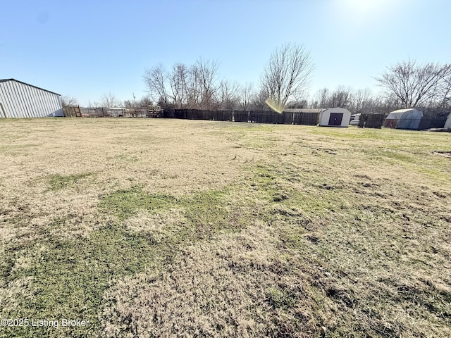 view of yard featuring an outbuilding, fence, and a shed