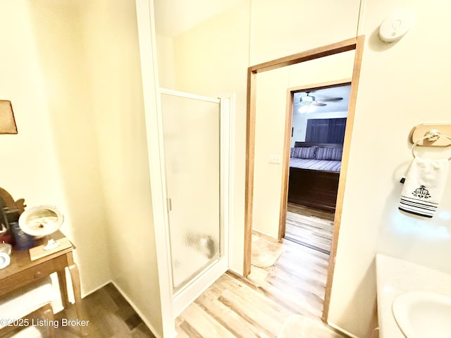 full bath with vanity, wood finished floors, and a stall shower