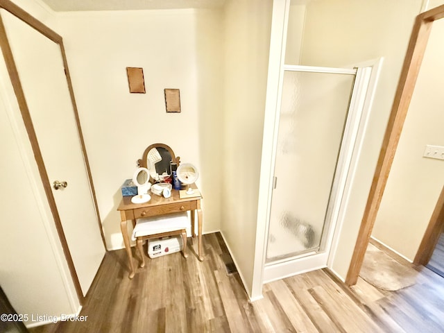 bathroom with a shower stall and wood finished floors