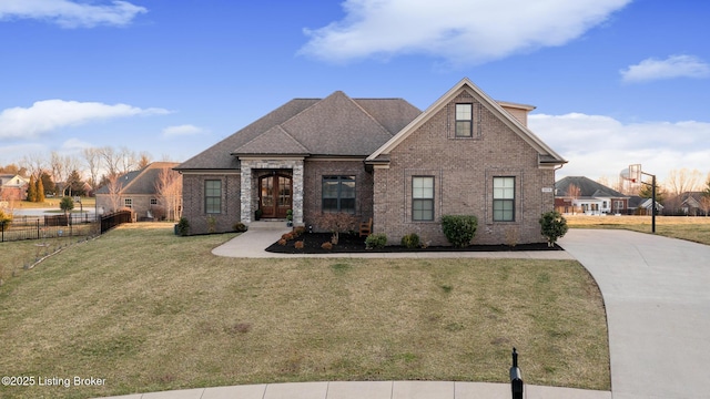 view of front of house featuring fence, concrete driveway, a front yard, brick siding, and a shingled roof