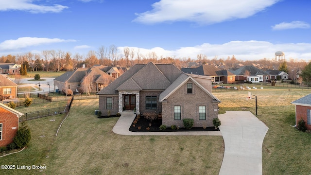 view of front of property featuring brick siding, a front lawn, fence, and a residential view