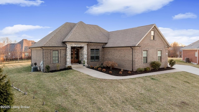 french country style house with cooling unit, brick siding, a front yard, and a shingled roof