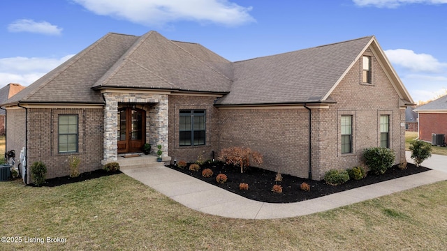 view of front of home with cooling unit, roof with shingles, a front lawn, french doors, and brick siding