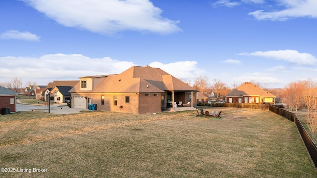 rear view of property with a lawn, driveway, a patio, central AC, and fence