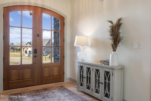 foyer entrance featuring wood finished floors, arched walkways, and french doors