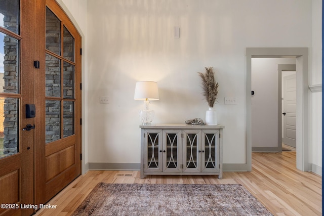 entryway featuring visible vents, baseboards, and wood finished floors