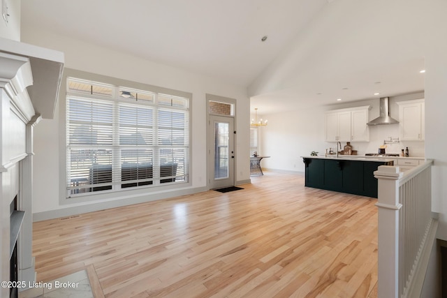 unfurnished living room with recessed lighting, light wood-type flooring, baseboards, and an inviting chandelier