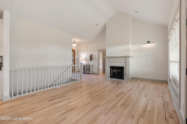 unfurnished living room with a fireplace, high vaulted ceiling, baseboards, and wood finished floors