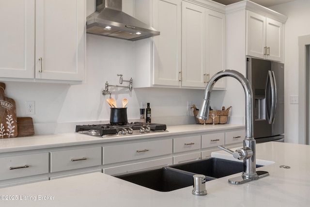 kitchen featuring light countertops, white cabinets, wall chimney exhaust hood, and appliances with stainless steel finishes