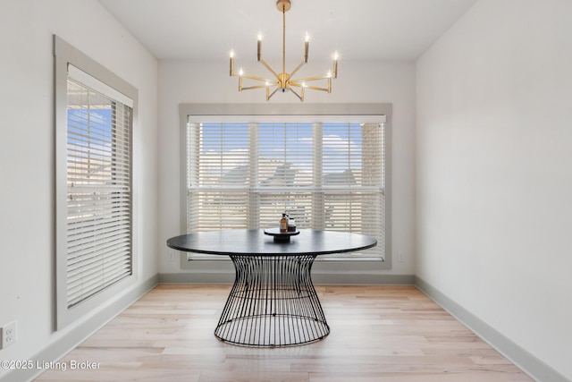 dining area with light wood-style flooring, an inviting chandelier, and baseboards