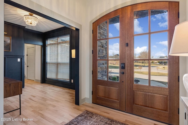 foyer featuring a notable chandelier, light wood-style floors, plenty of natural light, and french doors