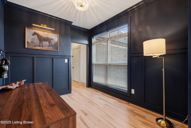 interior space featuring light wood-style floors, crown molding, and a decorative wall