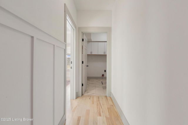 corridor with baseboards and light wood-style flooring