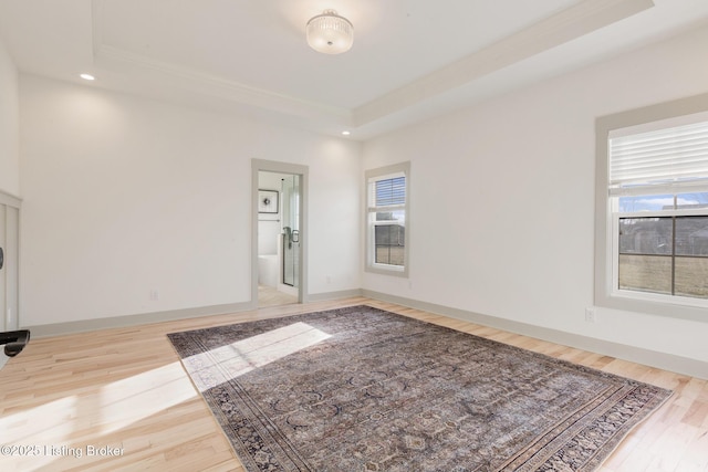 spare room with recessed lighting, baseboards, a raised ceiling, and wood finished floors