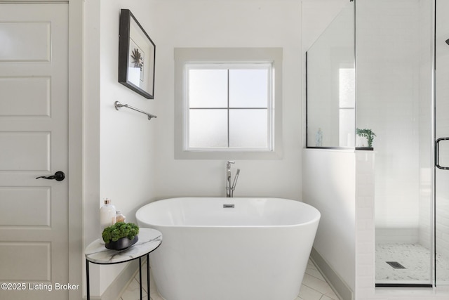 full bathroom featuring baseboards, a freestanding bath, and a stall shower