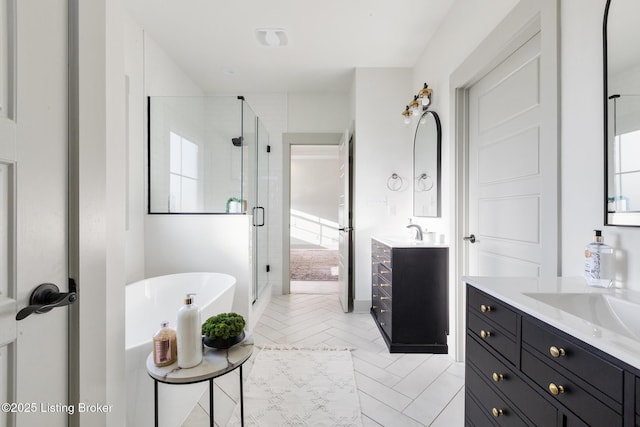 bathroom featuring a soaking tub, two vanities, a stall shower, and a sink