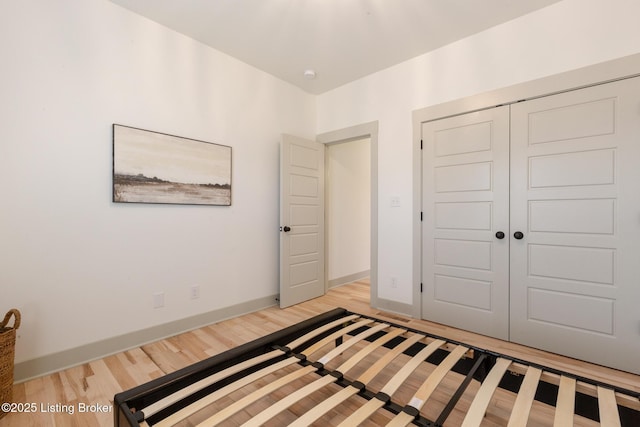 unfurnished bedroom with baseboards, a closet, and light wood finished floors