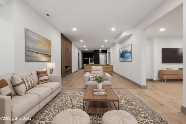 living area featuring recessed lighting, baseboards, light wood-style flooring, and a fireplace