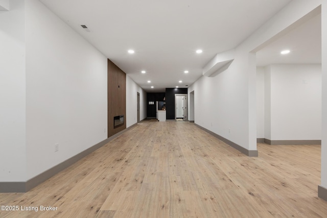 unfurnished living room featuring recessed lighting, light wood-style flooring, a fireplace, and baseboards