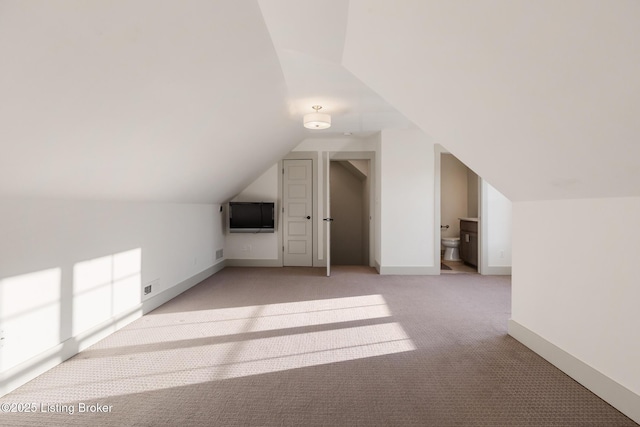 additional living space featuring light colored carpet, lofted ceiling, and baseboards