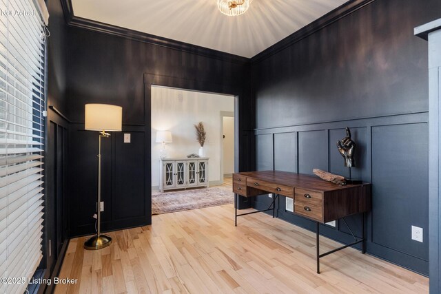 entryway with ornamental molding, wood finished floors, and a decorative wall