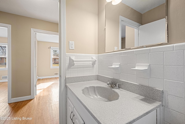 bathroom featuring visible vents, vanity, tile walls, and wood finished floors