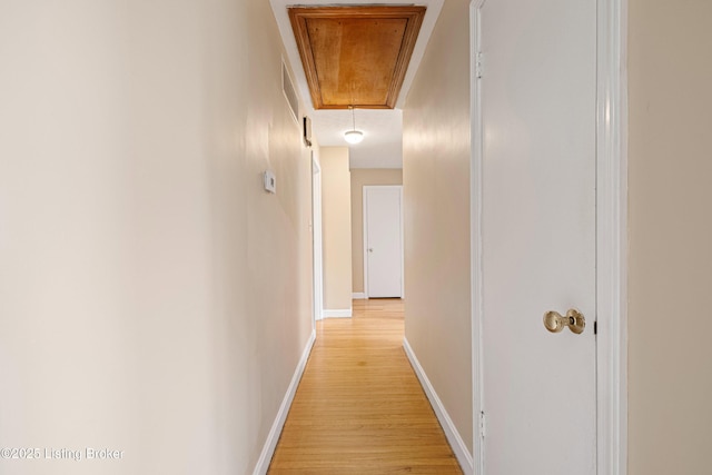 corridor featuring baseboards, attic access, and light wood-style flooring