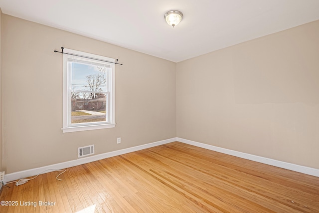 empty room featuring baseboards, visible vents, and wood-type flooring