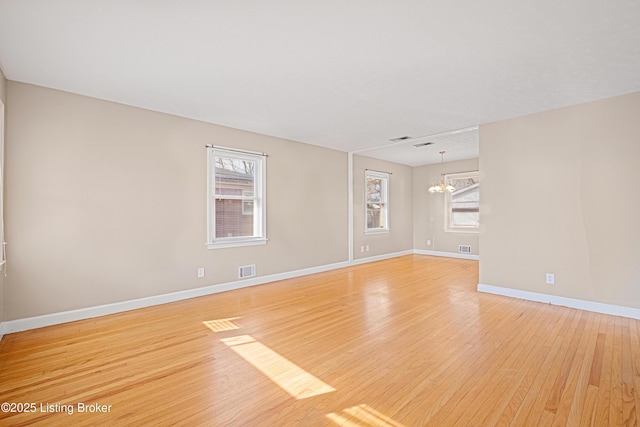 unfurnished room with a chandelier, visible vents, baseboards, and light wood-style floors