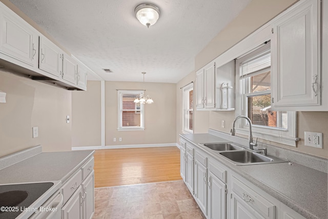 kitchen featuring hanging light fixtures, white cabinets, a textured ceiling, and a sink