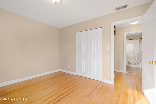 unfurnished bedroom with visible vents, baseboards, a closet, and wood finished floors