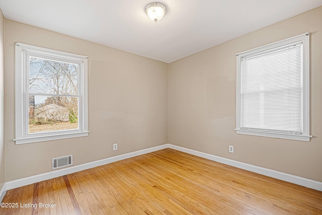 spare room featuring visible vents, baseboards, and wood-type flooring