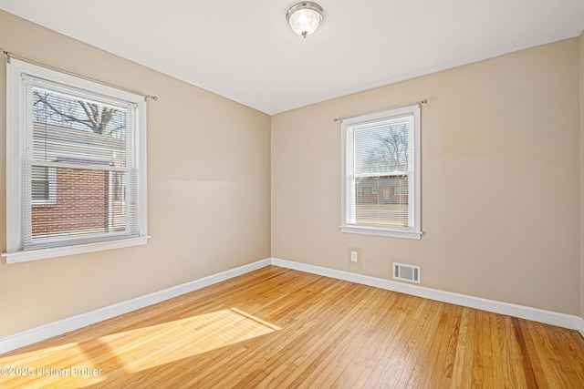 unfurnished room featuring visible vents, baseboards, and wood finished floors